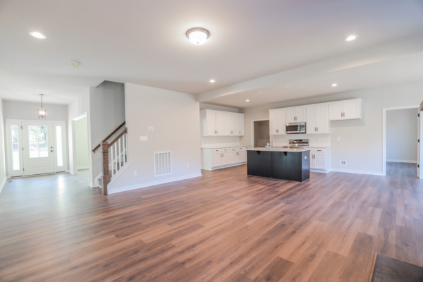 Spacious modern kitchen and living area with hardwood floors, white cabinets, and a central island under bright lighting—Photo Gallery.