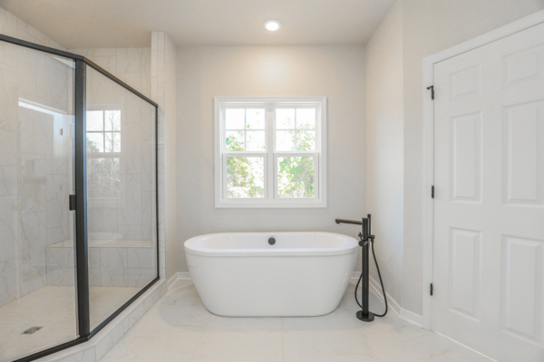 Minimalist bathroom with a standalone bathtub, glass-enclosed shower, and window lighting up this photo gallery-worthy space.