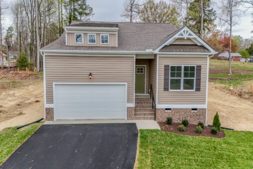Charming single-story tan house with white garage, green door, and landscaped yard—perfect new home in Richmond, VA.
