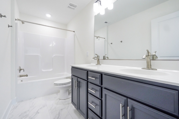 Modern bathroom with a marble floor, dual-sink vanity, and a shower-tub combo under bright lighting.