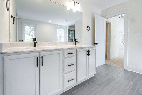 Modern bathroom with a double sink vanity, white cabinetry, black fixtures, and a mirror.