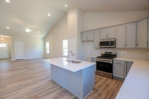 Modern kitchen and living room with a center island, stainless steel appliances, and wood flooring.