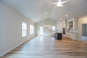 Spacious open-plan kitchen and living area with wood floors, light walls, and ceiling fan.
