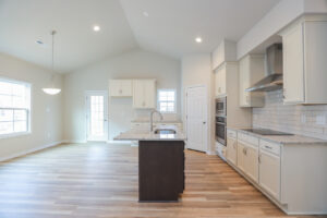 Modern kitchen with white cabinets, center island, stainless steel appliances, and light wood flooring.