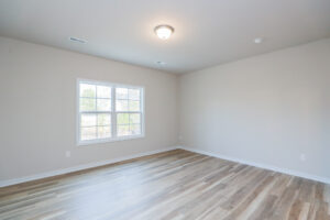 Empty room with light wood flooring, beige walls, and a window—ideal for new homes in Richmond VA.