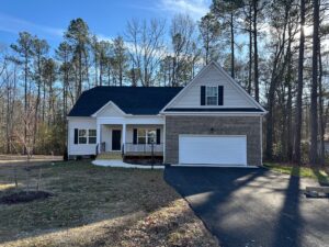A modern suburban house in Patrick Henry Heights with a front porch, garage, and driveway surrounded by tall trees.