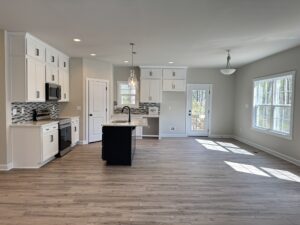 Modern kitchen in new homes in Richmond VA with white cabinets, black island, and large windows for natural light.