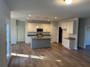 Modern kitchen in Lot 57, Patrick Henry Heights with white cabinets, wood floors, and pendant lighting in a bright open space.