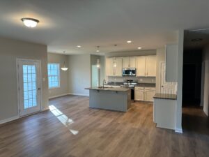 Modern kitchen in Patrick Henry Heights, with white cabinets, island, and stainless steel appliances by a bright dining area.