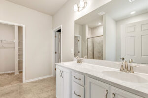 Bright bathroom in Patrick Henry Heights with double sinks, marble countertop, glass shower; closet to the left.