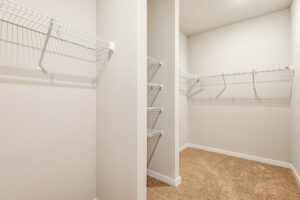 Spacious walk-in closet in Patrick Henry Heights Lot 57 with beige carpet and white wire shelves.