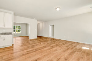 Modern empty room with wood flooring in Lot 57, Patrick Henry Heights, view of kitchen and adjoining rooms.