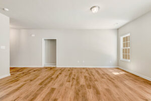 Bright empty room in Lot 57, Patrick Henry Heights with beige walls, wood flooring, window, and ceiling light fixture.