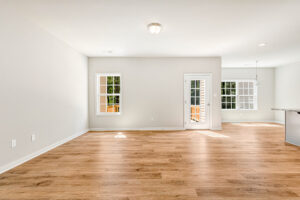 Bright, empty room in Patrick Henry Heights Lot 57 with wood floors, white walls, and large windows full of natural light.