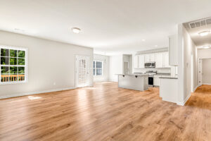 Bright, open-plan living area in Lot 57, Patrick Henry Heights, with wood floors, modern kitchen, and backyard view.