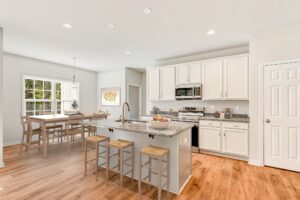 Bright modern kitchen in Lot 57, Patrick Henry Heights, featuring white cabinets, granite island, and large windows.