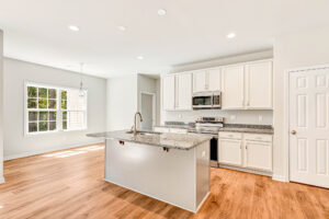 Modern kitchen in Patrick Henry Heights, white cabinets, granite island, stainless appliances, and bright windows.