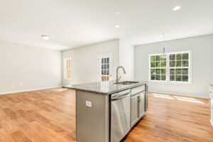 Bright, modern kitchen in Patrick Henry Heights, Lot 57 with granite island, stainless appliances, and large windows.