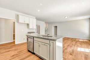 Modern kitchen in Patrick Henry Heights, Lot 57, with granite island, white cabinets, and wood flooring.