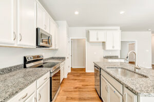 Bright modern kitchen in Patrick Henry Heights with white cabinets, granite counters, and wood flooring.