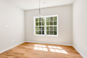 Empty room in Patrick Henry Heights, with light wood floors, white walls, window, and ceiling light. Lot 57.