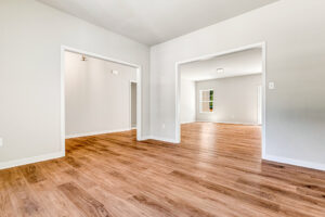 Spacious, empty room with light gray walls, wood flooring, and white trim in Patrick Henry Heights Lot 57.