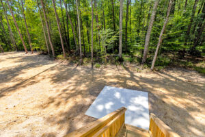 View from wooden steps to concrete pad on Lot 57, surrounded by trees in Patrick Henry Heights.