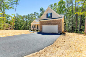 Modern suburban house in Patrick Henry Heights with brick exterior, front porch, garage, and trees on Lot 57.