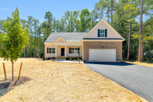 Single-story home in Patrick Henry Heights, Lot 57, with garage, porch, driveway, and a newly landscaped yard.