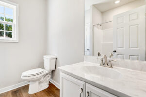 Bright bathroom in Lot 57, Patrick Henry Heights, with white sink, wood floor, and window with natural light.