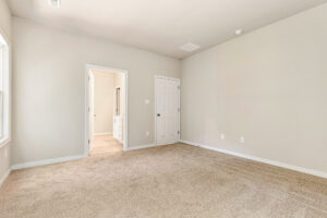 Bright beige carpeted room in Patrick Henry Heights, Lot 57, with white walls, two doors, and natural light.