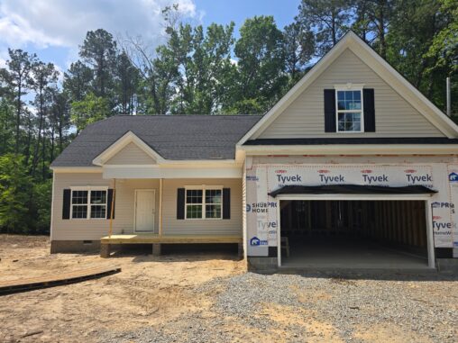 A newly constructed house on Lot 57 with a covered porch and unfinished garage in Patrick Henry Heights’ wooded area.