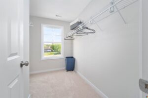 Empty walk-in closet with wire shelves, a blue hamper, and a window overlooking Lot 22 in Poplar Village.