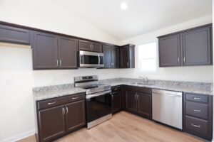 Modern kitchen in new homes in Richmond VA features dark cabinets, granite countertops, and stainless steel appliances.