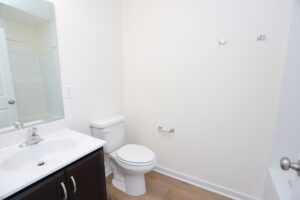 A clean, modern bathroom in new homes in Richmond VA features light walls, a toilet, sink, and wood-style flooring.