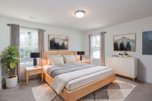 Bright bedroom with wooden bed, neutral bedding, and plants—perfect for new homes in Richmond VA.