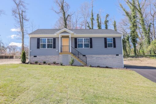 Single-story gray house with black shutters and a lawn—perfect for new homes in Richmond VA, under a blue sky.