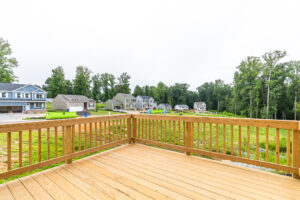 View from a wooden deck overlooking Lot 22 in Poplar Village, with houses and trees in the background.