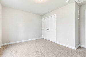 Empty room in Poplar Village, Lot 22, with beige carpet, light walls, and a closed double white closet door.