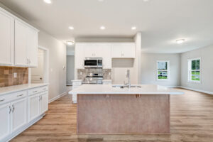 Modern kitchen in Poplar Village with white cabinets, stainless steel appliances, and a large island with a sink.