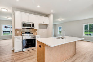 Modern kitchen in Poplar Village with white cabinets, stainless appliances, and a large island with a sink.
