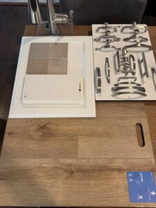 Kitchen design samples for Lot 22: tiles, faucet, and handles on a wooden table in Poplar Village.