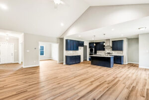 Spacious modern kitchen and living area with wood floors, navy cabinets, and white walls.