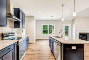 Modern kitchen with dark cabinets, granite countertops, island sink, and stainless steel appliances.