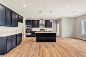 Modern kitchen with dark cabinets, stainless steel appliances, island, and light wood floors.