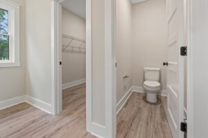 A white toilet in a small bathroom next to a walk-in closet, typical of new homes in Richmond VA.