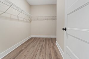 Spacious walk-in closet with beige walls, wood floor, and white wire shelving in new homes in Richmond VA.
