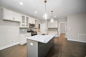 Modern kitchen at Shirley Commons with marble island, stainless steel appliances, and gray tile backsplash.