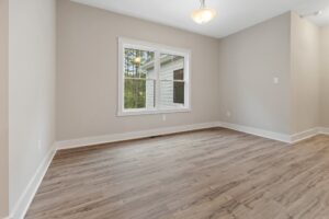 Bright empty room with light wood flooring, perfect for new homes in Richmond VA, features beige walls and a window.