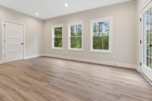 Bright, empty room in new homes in Richmond VA with light wood floors, beige walls, and windows facing greenery.